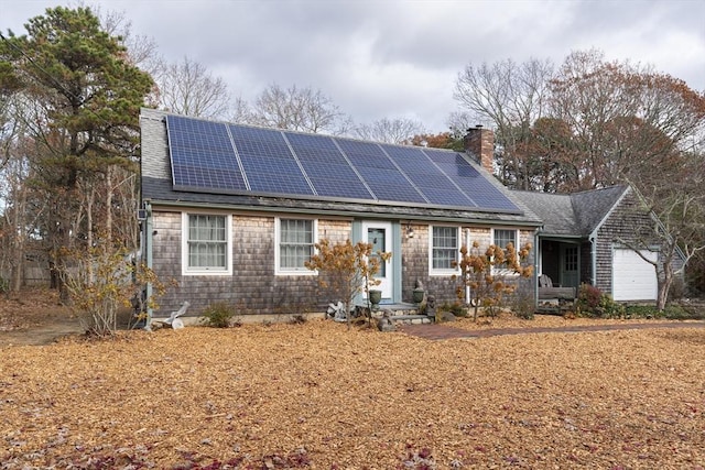 view of front of property featuring a shingled roof, a chimney, and solar panels