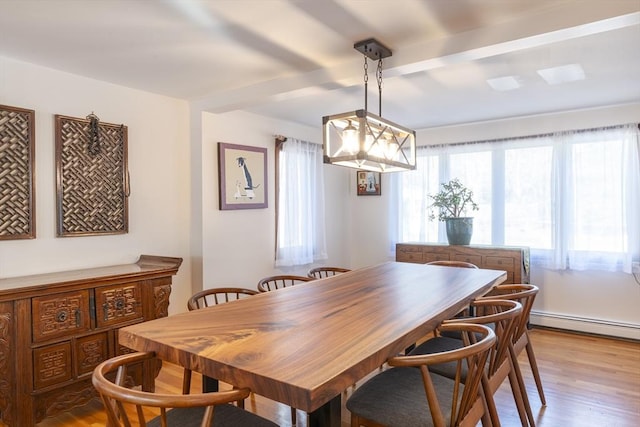 dining area featuring a baseboard radiator, beamed ceiling, and light wood-style flooring