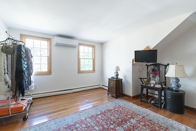 interior space with a wall unit AC, wood finished floors, and baseboards