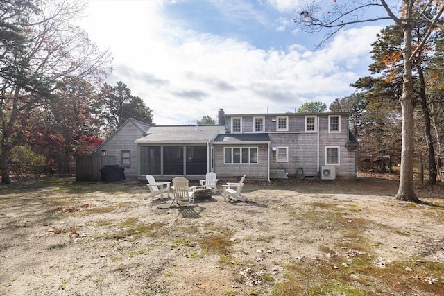 back of property with a sunroom, a chimney, and a fire pit