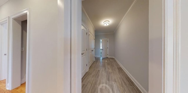 corridor featuring ornamental molding and light hardwood / wood-style flooring