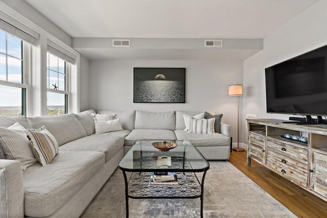 living room with visible vents, baseboards, and wood finished floors