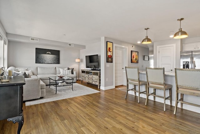 living area with visible vents, baseboards, and wood finished floors