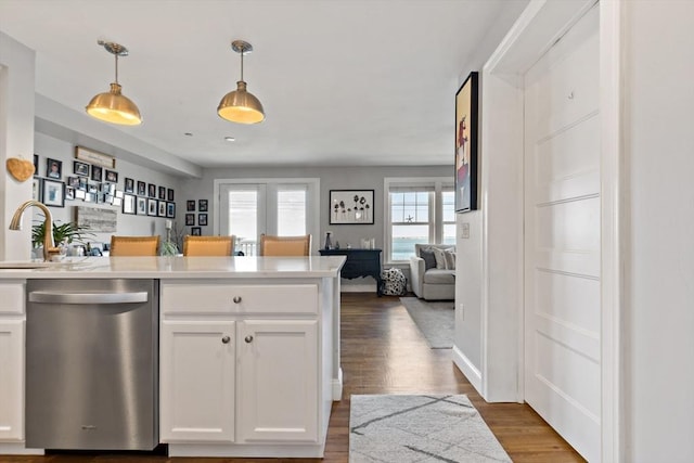 kitchen with dark wood finished floors, white cabinets, stainless steel dishwasher, decorative light fixtures, and open floor plan