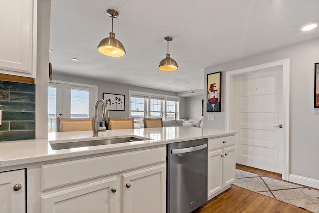 kitchen with decorative light fixtures, a sink, light countertops, and stainless steel dishwasher