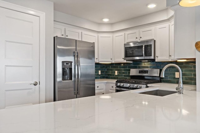 kitchen with a sink, stainless steel appliances, tasteful backsplash, and white cabinets