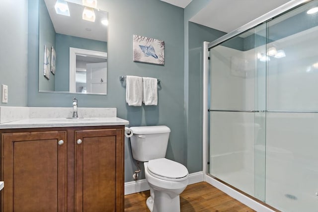 full bathroom with toilet, a stall shower, wood finished floors, baseboards, and vanity