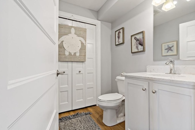 bathroom featuring toilet, vanity, and wood finished floors