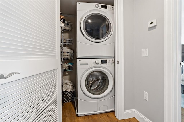 laundry room featuring laundry area, wood finished floors, and stacked washer and clothes dryer