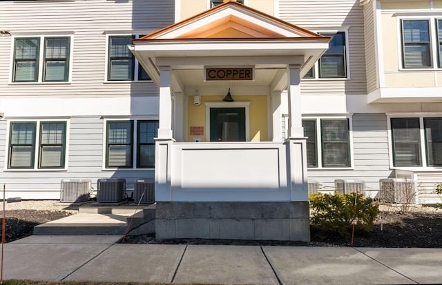 doorway to property featuring stucco siding and central AC unit