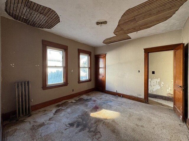 unfurnished room featuring light carpet, radiator heating unit, and a textured ceiling