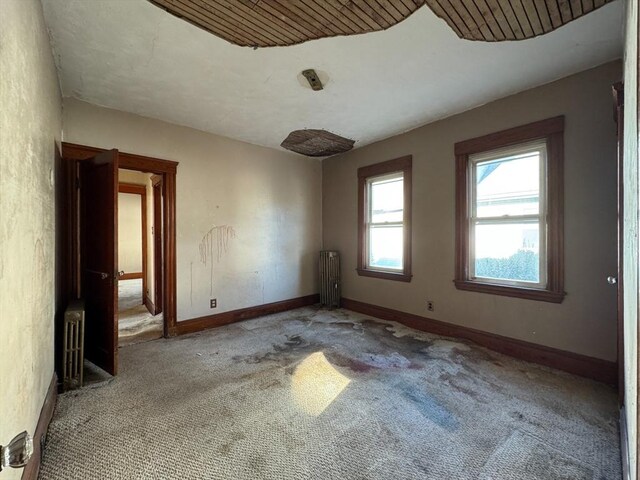 spare room with light colored carpet and radiator heating unit