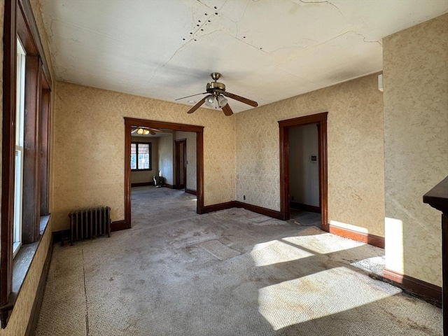 carpeted empty room with radiator and ceiling fan