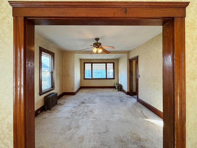 carpeted spare room with plenty of natural light, ceiling fan, and radiator