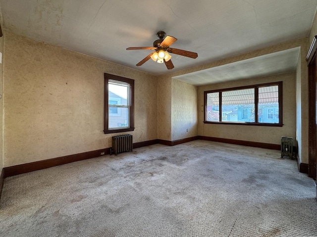 carpeted empty room with ceiling fan and radiator heating unit