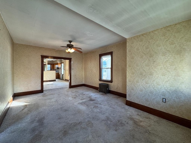 carpeted empty room with ceiling fan and radiator heating unit