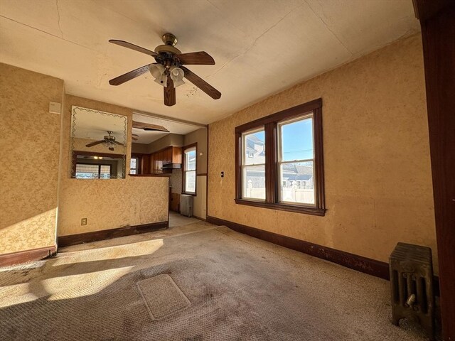 carpeted empty room featuring ceiling fan and radiator heating unit