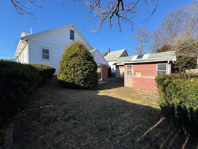 view of side of property featuring a storage unit and a lawn