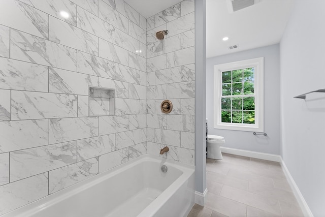 bathroom with toilet, tiled shower / bath, and tile patterned floors