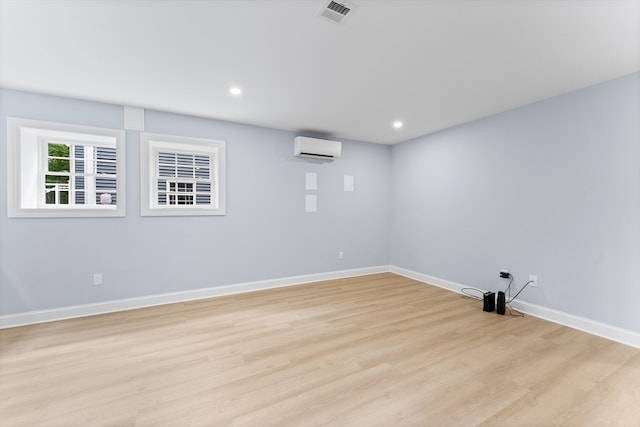 empty room with light hardwood / wood-style flooring and an AC wall unit