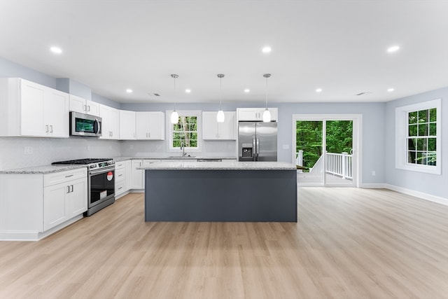 kitchen with light hardwood / wood-style flooring, white cabinets, appliances with stainless steel finishes, light stone countertops, and sink