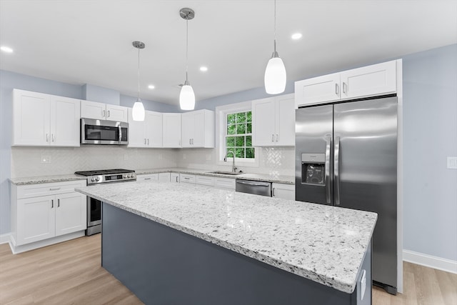 kitchen with sink, decorative light fixtures, appliances with stainless steel finishes, decorative backsplash, and light hardwood / wood-style floors