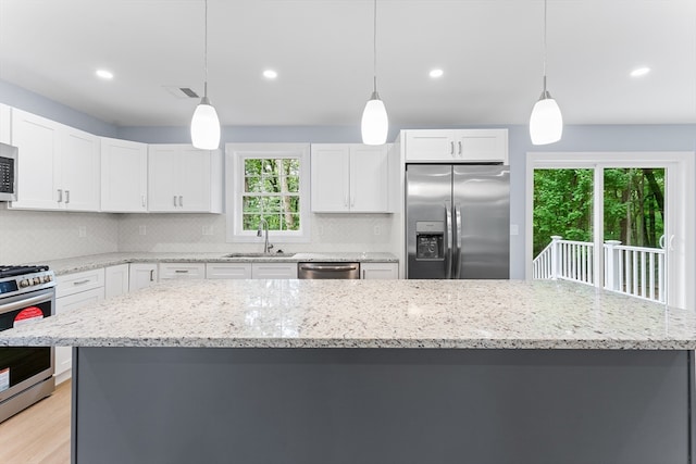 kitchen with stainless steel appliances, plenty of natural light, tasteful backsplash, and decorative light fixtures