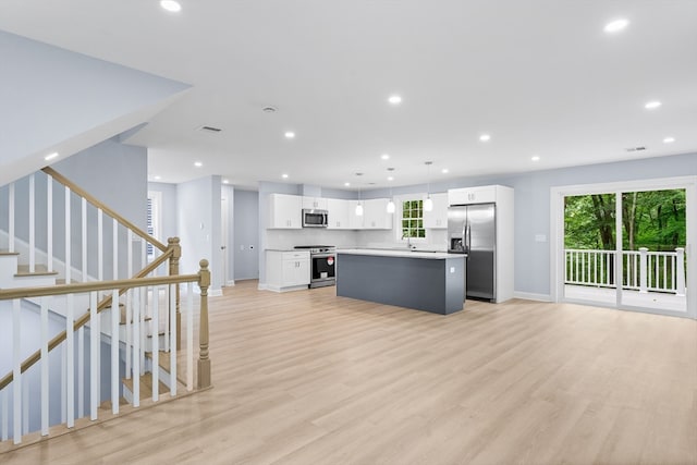 kitchen with light wood-type flooring, stainless steel appliances, a kitchen island, and white cabinetry