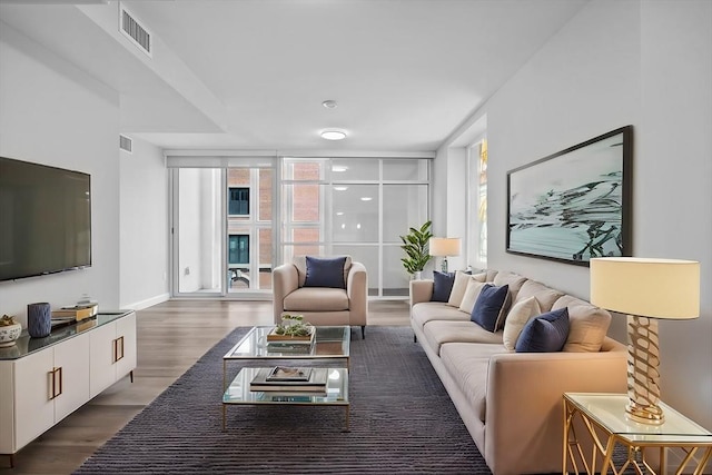 living area with visible vents, floor to ceiling windows, baseboards, and wood finished floors