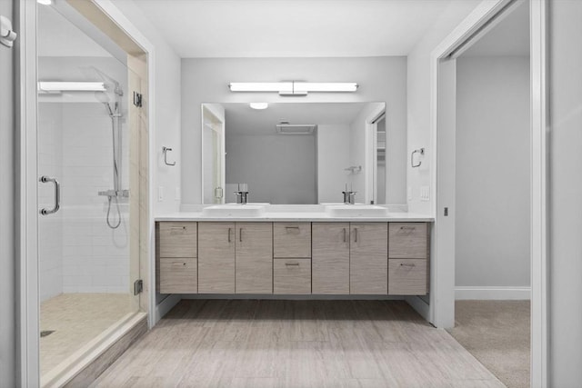 full bath featuring a sink, baseboards, a shower stall, and double vanity