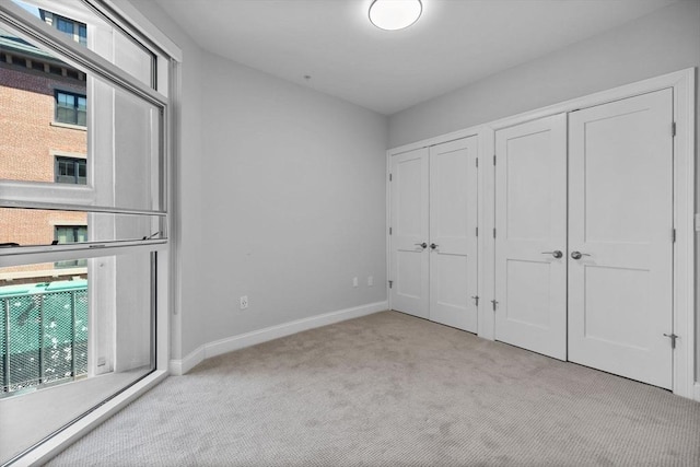 unfurnished bedroom featuring carpet flooring, baseboards, and multiple closets