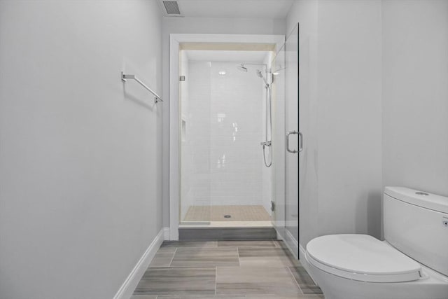 bathroom featuring visible vents, baseboards, toilet, and a shower stall