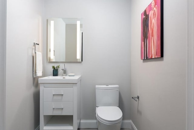 bathroom with toilet, vanity, and baseboards