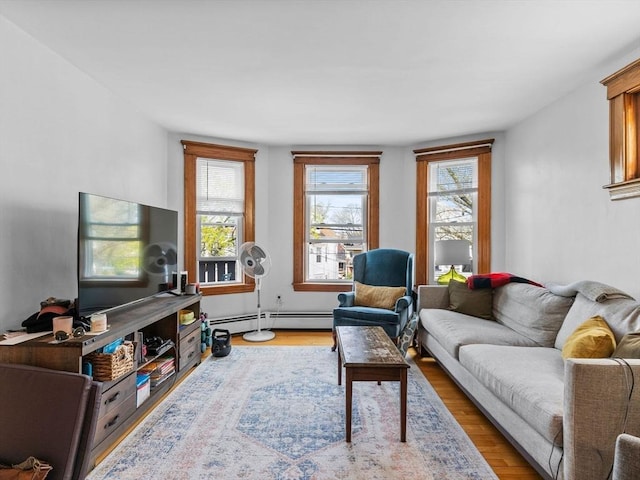 living room featuring a healthy amount of sunlight, baseboard heating, and wood finished floors