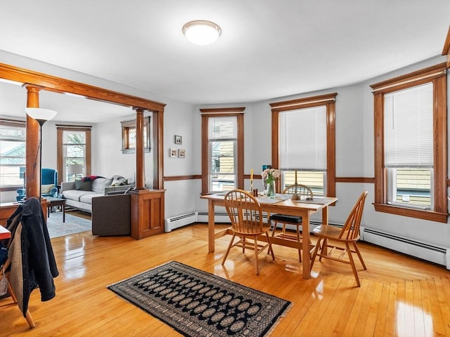dining room featuring plenty of natural light, light wood finished floors, and decorative columns