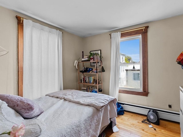 bedroom with a baseboard radiator and hardwood / wood-style flooring