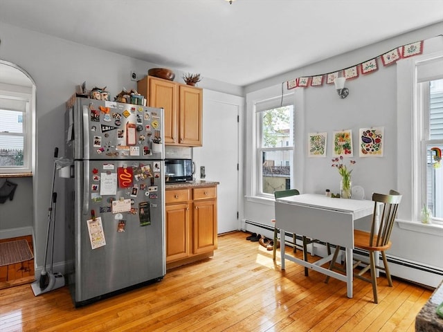 kitchen featuring light countertops, freestanding refrigerator, a baseboard heating unit, and light wood-type flooring