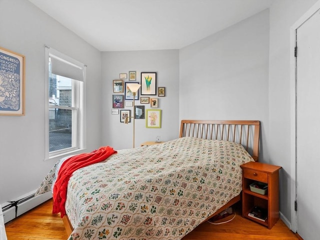 bedroom with a baseboard heating unit and wood finished floors