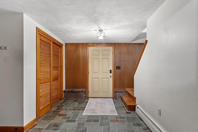 15 Greenbrook Rd, Hamilton, MA 01982 - foyer featuring stairs, dark stone finish flooring, wood walls, a baseboard radiator, and a textured ceiling