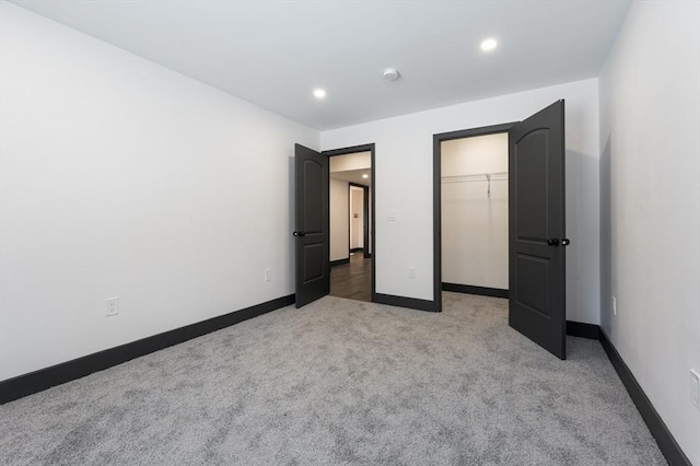 unfurnished bedroom featuring a closet, light carpet, and a walk in closet