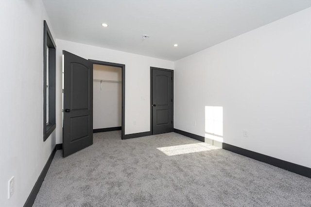 unfurnished bedroom with light colored carpet and a closet