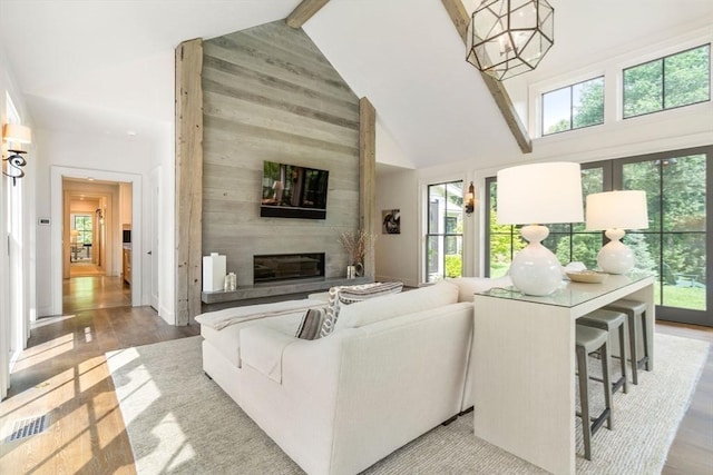 living area with a wealth of natural light, high vaulted ceiling, and wood finished floors