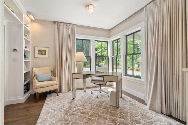 home office featuring wood finished floors, baseboards, and built in shelves