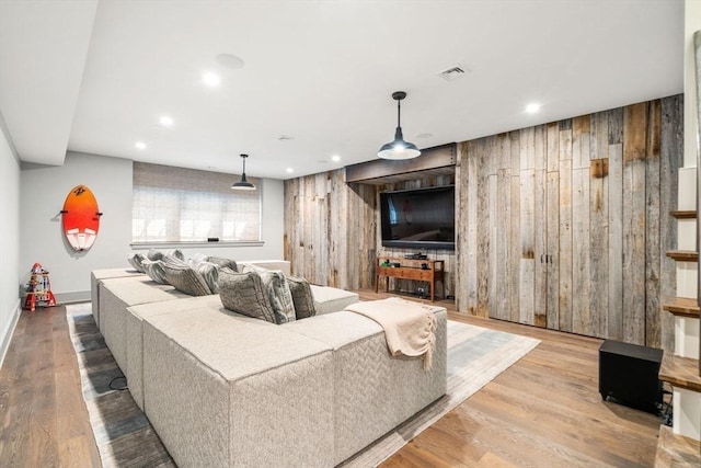 living area with recessed lighting, baseboards, visible vents, wooden walls, and wood finished floors