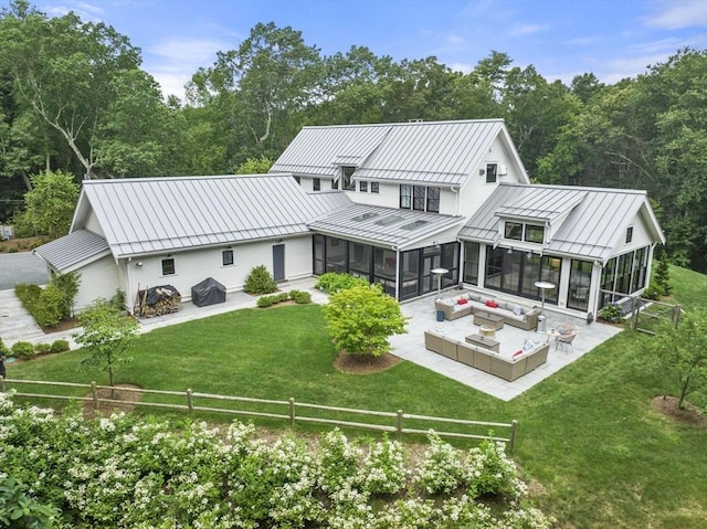 rear view of property featuring an outdoor living space, metal roof, a fenced backyard, a sunroom, and a standing seam roof