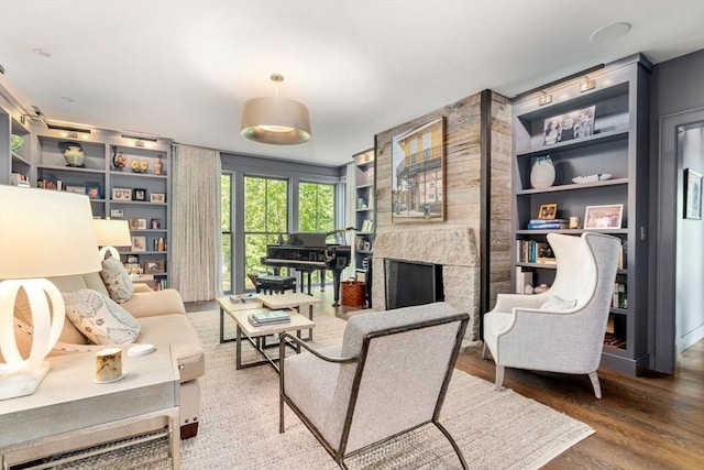 living area with wood finished floors, built in features, and a fireplace
