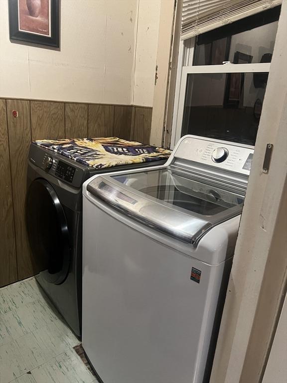 washroom featuring wooden walls and separate washer and dryer