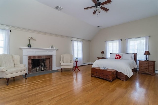 bedroom with a brick fireplace, visible vents, vaulted ceiling, and light wood-type flooring