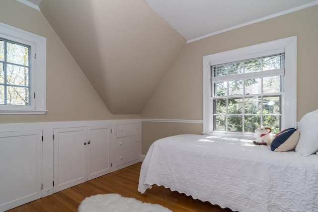 bedroom with wood finished floors, crown molding, and vaulted ceiling