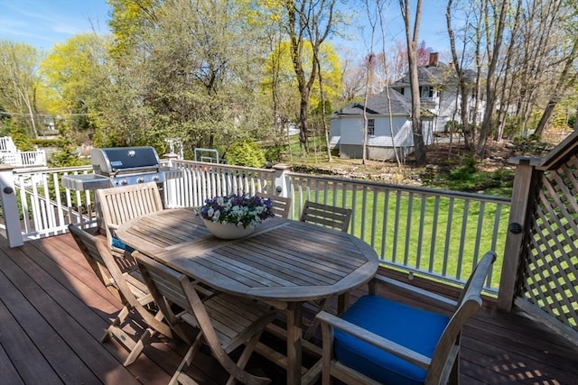 wooden terrace featuring a lawn, outdoor dining area, and grilling area